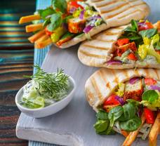 Veganský tofu gyros v pitě, podávaný s cuketovými chipsy a veganskými tzatziki